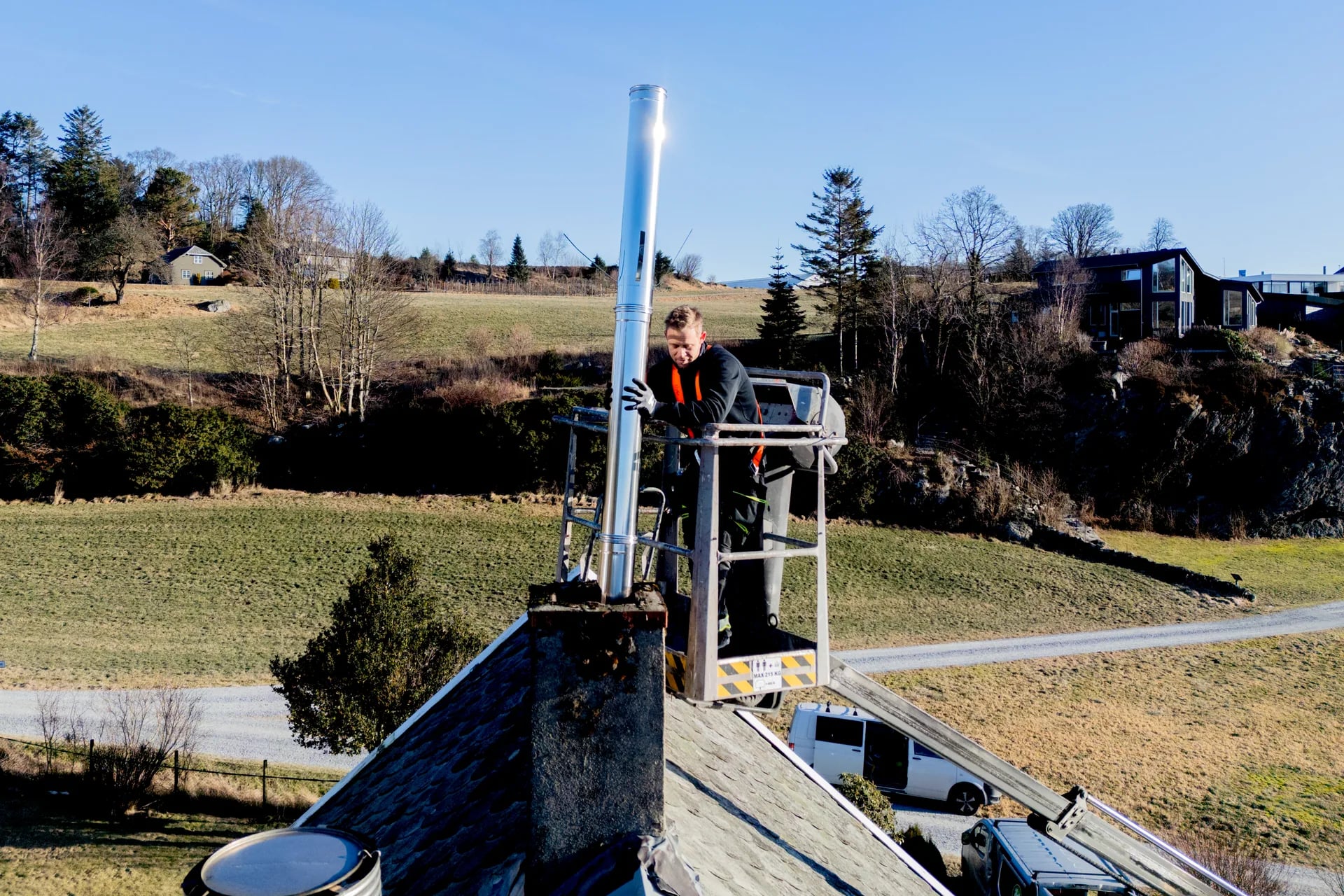Montør fører ny stålforing på pipen fra lift
